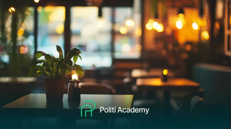 Um interior de café mal iluminado com uma planta em vaso sobre uma mesa e luzes desfocadas ao fundo. Logotipo e texto na parte inferior dizem "Politi Academy.