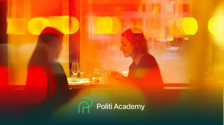 Duas pessoas sentadas à mesa com taças de vinho em um ambiente bem iluminado. A cena está borrada com luzes brilhantes laranja e amarelas. O texto diz "Politi Academy" na parte inferior.