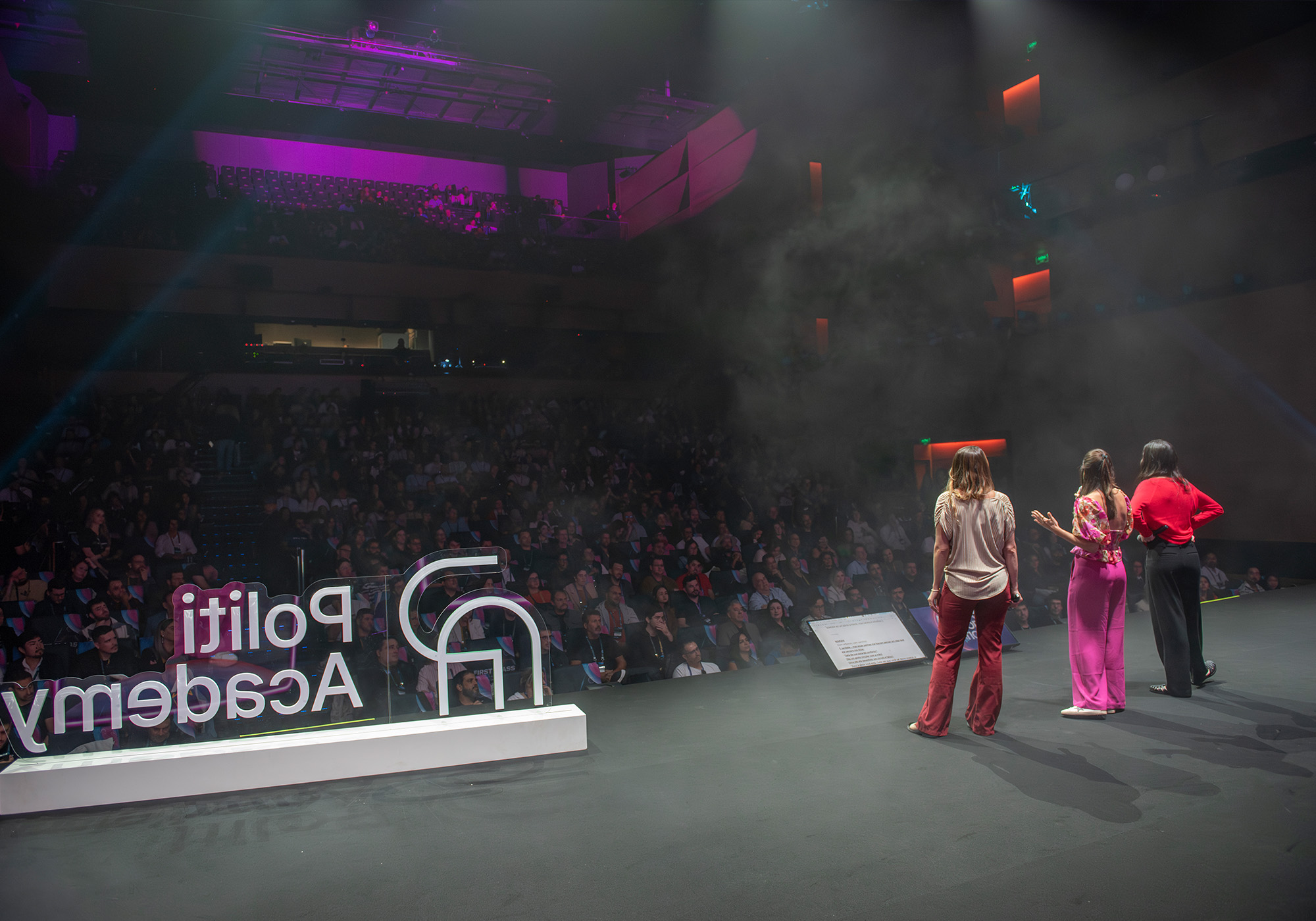 Três pessoas estão no palco, de frente para uma plateia em um grande auditório, com "PoliT Academy" e "Acelera Food Nation 2026" exibidos em cartazes ao lado.