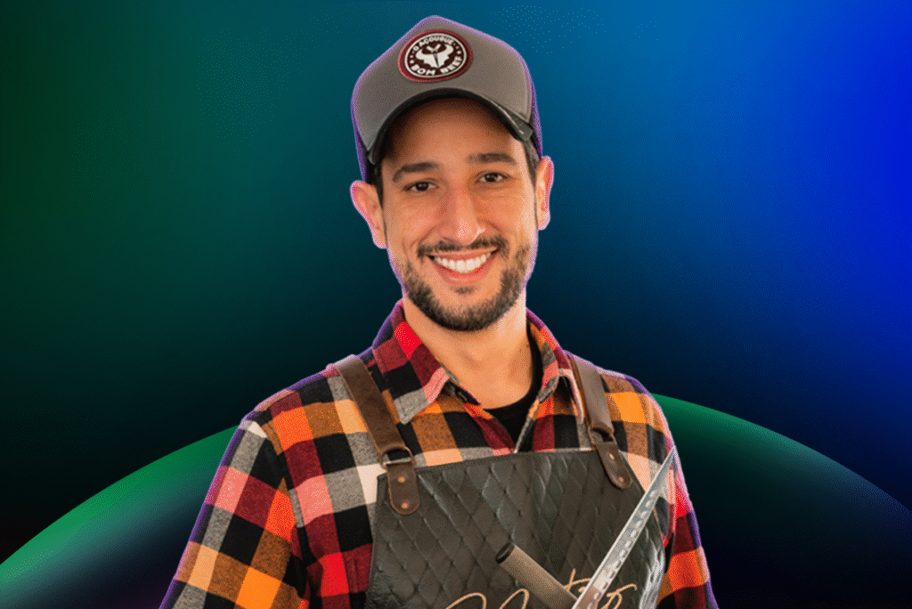 Um homem sorridente com uma camisa xadrez, avental e boné está em um fundo gradiente azul e verde, pronto para lhe dar as boas-vindas ao Acelera Food Nation - entre na lista de espera hoje mesmo!.