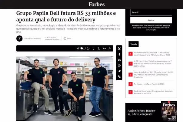Quatro homens vestindo camisetas pretas da Papila Deli estão de pé e sentados em uma cozinha comercial, posando para uma foto de grupo para um artigo da Forbes sobre o crescimento e o futuro da empresa na entrega de alimentos.