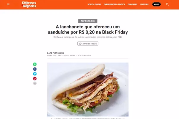 Captura de tela de um artigo de notícias que mostra um sanduíche em um prato, com uma manchete sobre uma loja que oferece um sanduíche por R$ 0,20 na Black Friday.