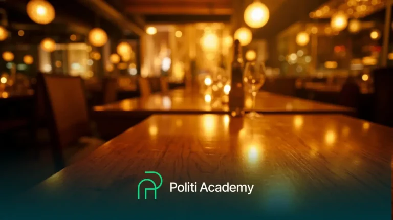 Um restaurante mal iluminado com taças e garrafas de vinho em uma mesa de madeira; o logotipo e o nome da Politi Academy aparecem na parte inferior.